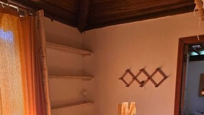 Une pièce avec une table et des bancs en bois, un tapis tissé et une étagère fixée au mur.