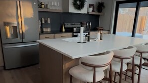 Une cuisine moderne dotée d’un îlot central, de tabourets de bar et d’une grande fenêtre.