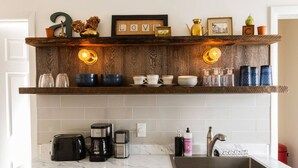 A kitchen with a marble countertop, a coffee maker, a toaster, a sink, and a shelf with various items. - Private Modern 3 Bed Apt Close to Downtown- 1st Flr (Torrington)