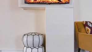 A flat-screen TV mounted on a white wall displaying a fireplace scene. - Private Modern 3 Bed Apt Close to Downtown- 1st Flr (Torrington)