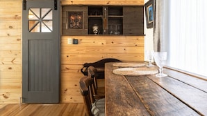 Un intérieur rustique en bois, agrémenté d’une porte coulissante de style grange, d’une table à manger en bois et de sets de table en fibres tressées, ainsi que d’un banc.