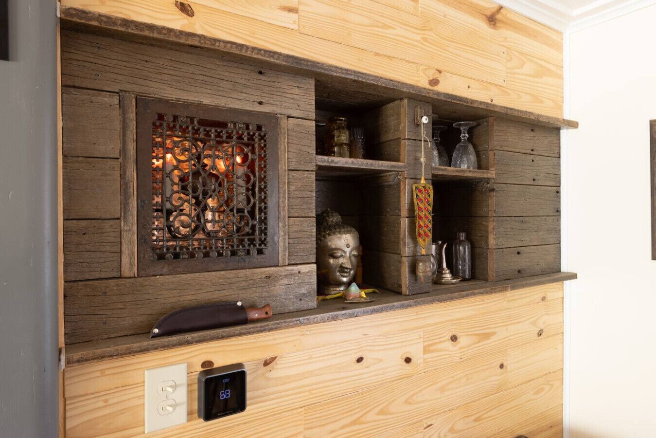 A wooden wall with a built-in fireplace, a Buddha statue, and various decorative items.