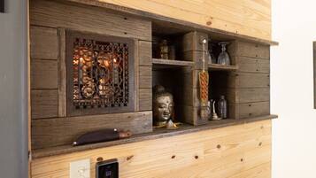 A wooden wall with a built-in fireplace, a Buddha statue, and various decorative items.