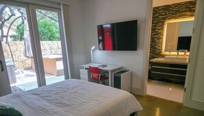 A bedroom with a bed, a desk, a TV, and a bathroom with a shower and sink. - Elysian Haven - Modern Urban Oasis in a Peaceful Neighborhood (San Antonio)