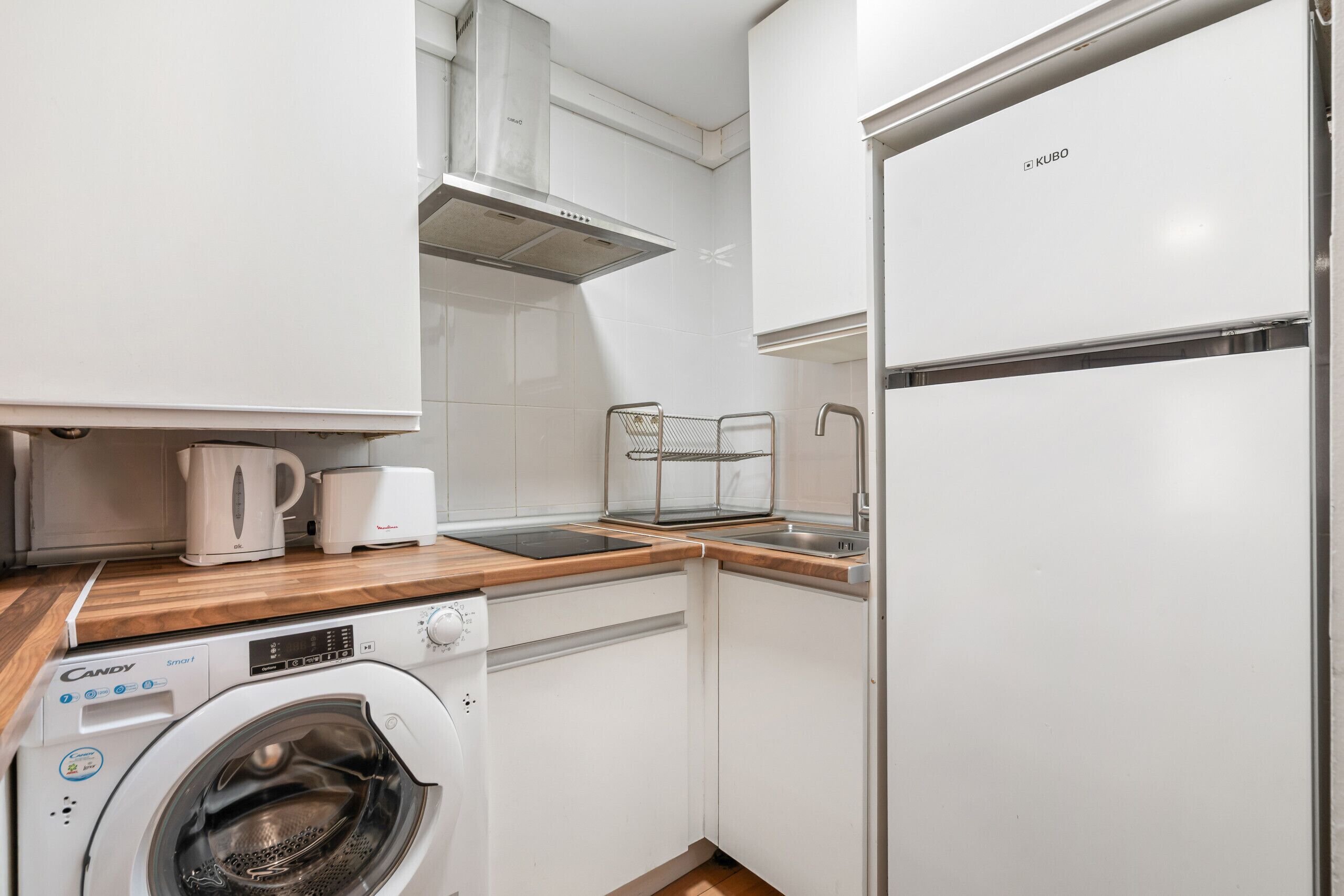 Een functionele keuken met een ingebouwde wasmachine, een broodrooster en een waterkoker.