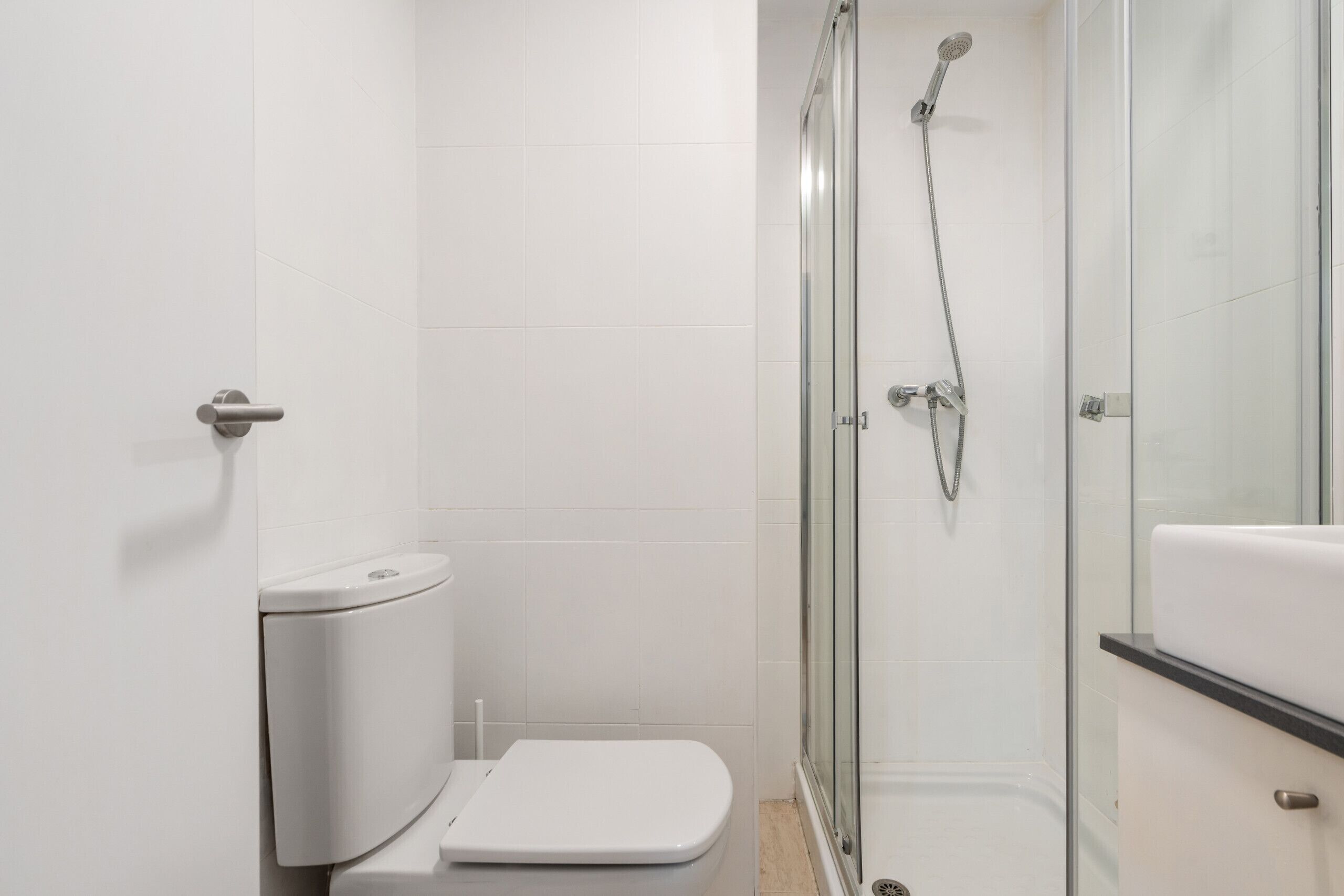 Un baño moderno con inodoro, cabina de ducha de vidrio y lavamanos.
