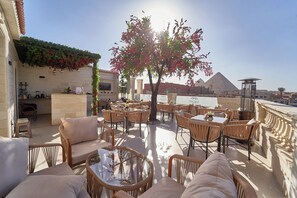 An outdoor seating area with wicker furniture and a view of the pyramids. - Ra Palace Pyramids View (Giza)