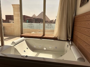 A bathtub with a view of The Palace Hotel and pyramids. - Ra Palace Pyramids View (Giza)