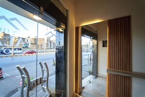A hotel entrance with a glass door, a wooden panel wall, and a view of the street outside. - Ra Palace Pyramids View (Giza)
