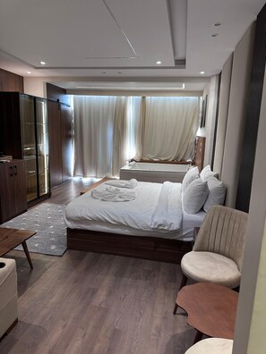 A modern bedroom with a large bed, a seating area, and a wardrobe. - Ra Palace Pyramids View (Giza)