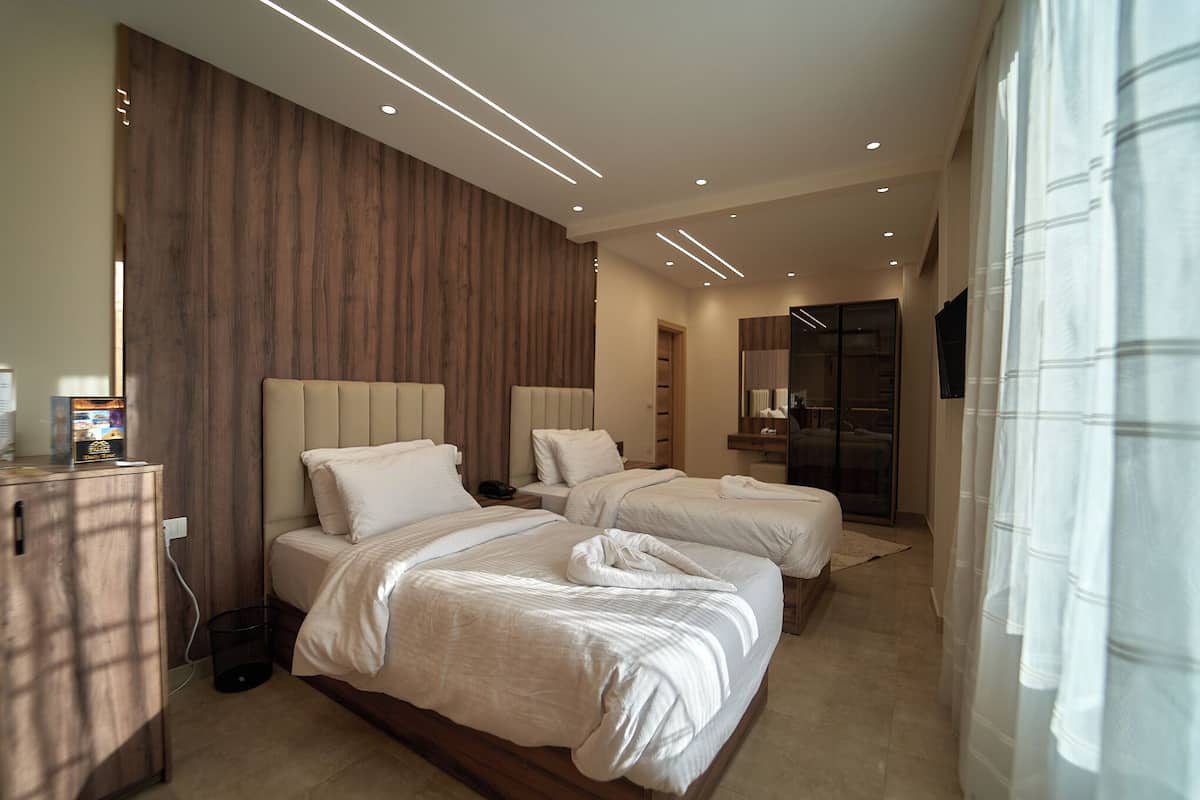 A modern hotel room with two beds, a wooden accent wall, and a built-in wardrobe.