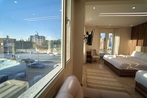 A hotel room with a large window, a bed, a desk, and a chair. - Ra Palace Pyramids View (Giza)