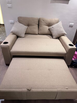 A beige sofa with a matching ottoman, two patterned pillows, and a small table with a pink polka dot tablecloth. - Ra Palace Pyramids View (Giza)