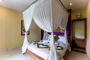 A four-poster bed with a canopy, a wooden headboard, and a floral bedspread. - Asri Sari Villa Ubud (Ubud)