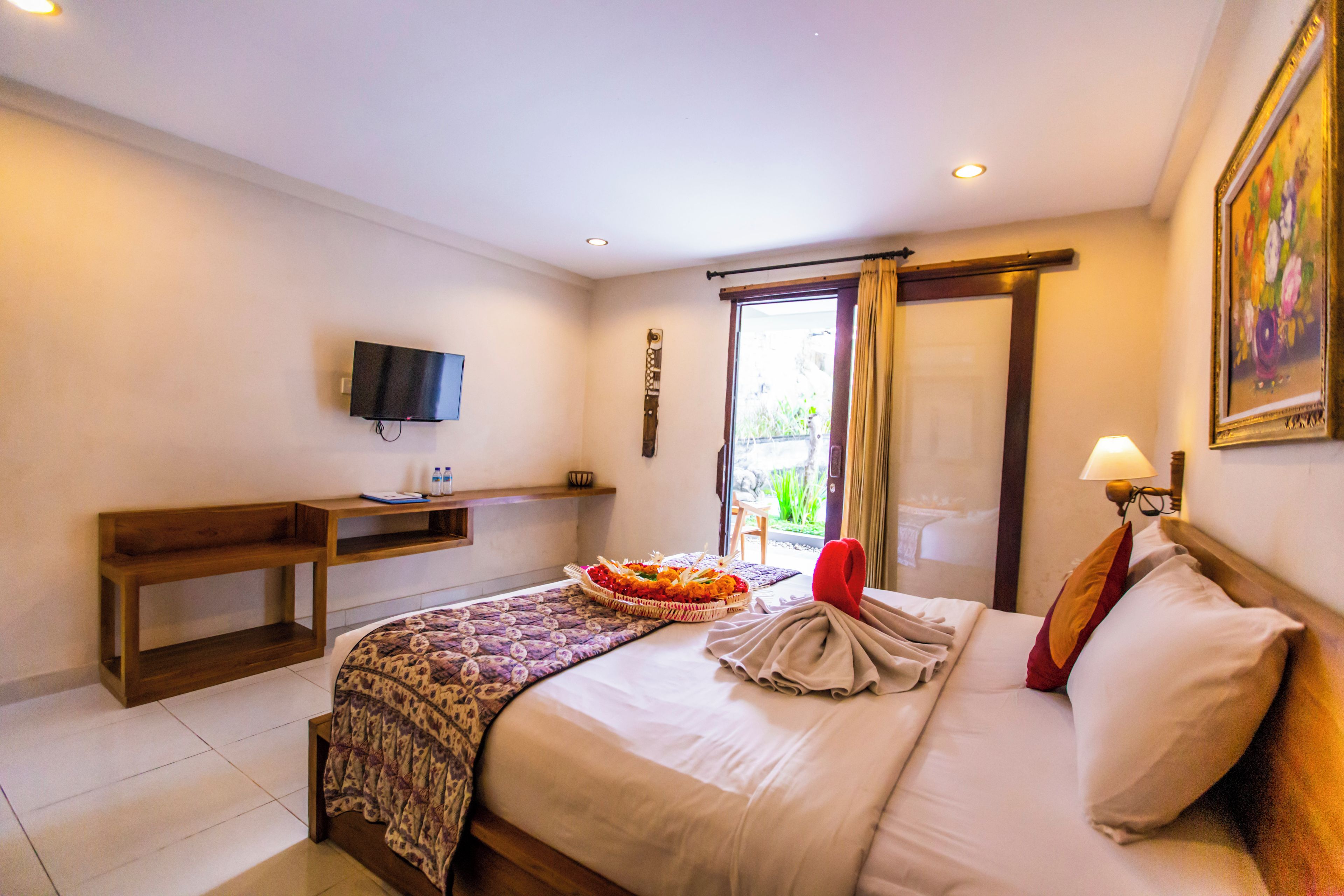 A hotel room with a bed, a desk, a television, and a window with curtains.