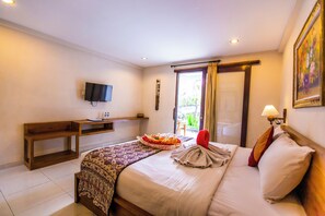 A hotel room with a bed, a desk, a television, and a window with curtains.