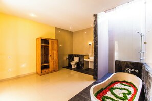 A modern bathroom with a freestanding bathtub, a wooden cabinet, and a toilet. - Asri Sari Villa Ubud (Ubud)