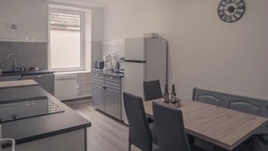A modern kitchen with a dining area, featuring a refrigerator, coffee maker, and a clock on the wall. - Elegant 70m² Castle view 6 persons Nature & Quiet Vosges (Senones)