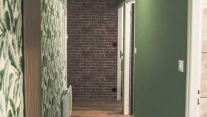A hallway with wooden flooring, green walls, and a brick accent wall. - Elegant 70m² Castle view 6 persons Nature & Quiet Vosges (Senones)