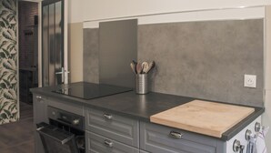 A modern kitchen with a stainless steel range hood, a wooden cutting board, and a utensil holder. - Elegant 70m² Castle view 6 persons Nature & Quiet Vosges (Senones)
