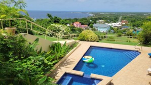 A swimming pool with a view of the ocean and surrounding greenery.