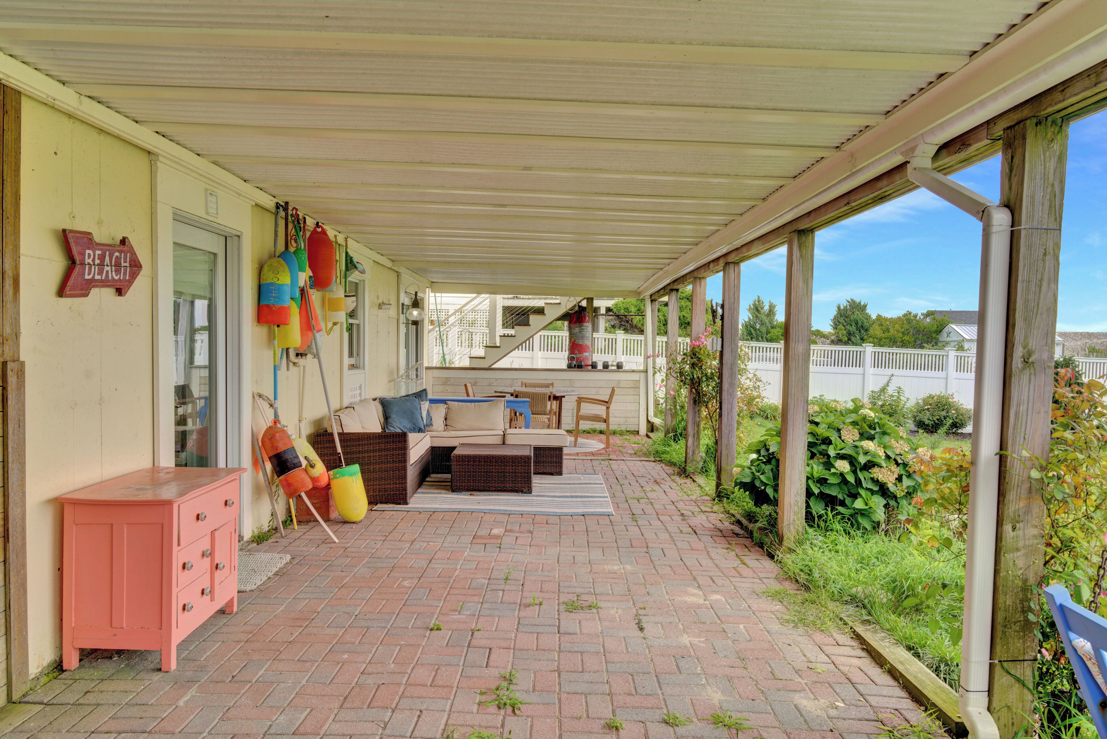 Eine überdachte Terrasse mit Gartenmöbeln, einem Holzschrank und bunten Bojen.