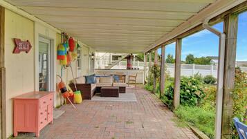 Eine überdachte Terrasse mit Gartenmöbeln, einem Holzschrank und bunten Bojen.