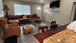 A living room with a sofa, coffee table, and a dining area with a table and chairs. - Fabulous 3-bedroom Hawaiian home. (Waimea)