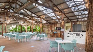 A spacious outdoor dining area with wooden tables and chairs, a bar area, and a sign reading "3 SIXTEEN BAR & BISTRO".