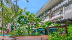 Ein Hotel mit Pool, Palmen und einem modernen Gebäude mit Balkonen.