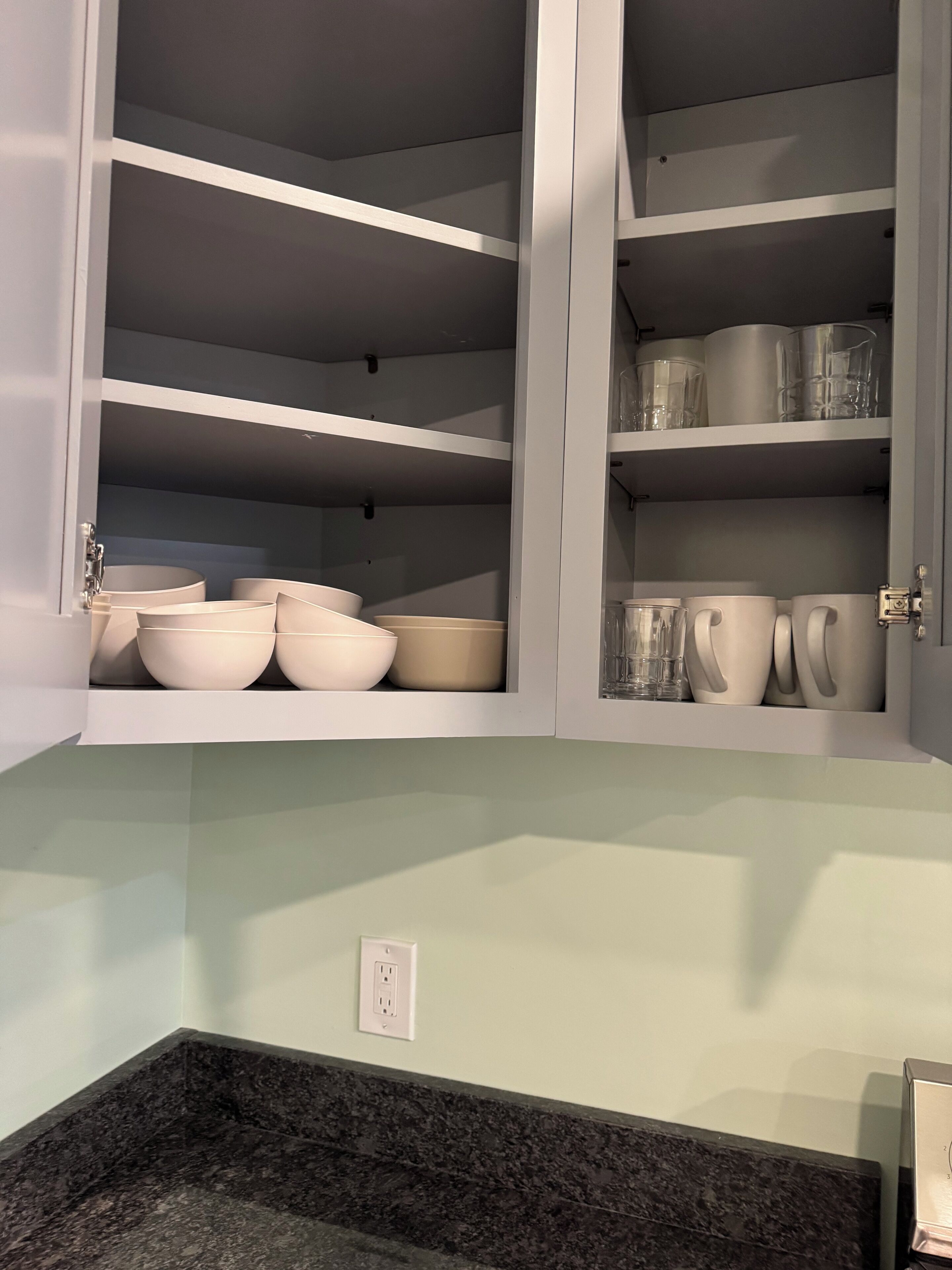 A kitchen with a built-in cabinet containing bowls and mugs.