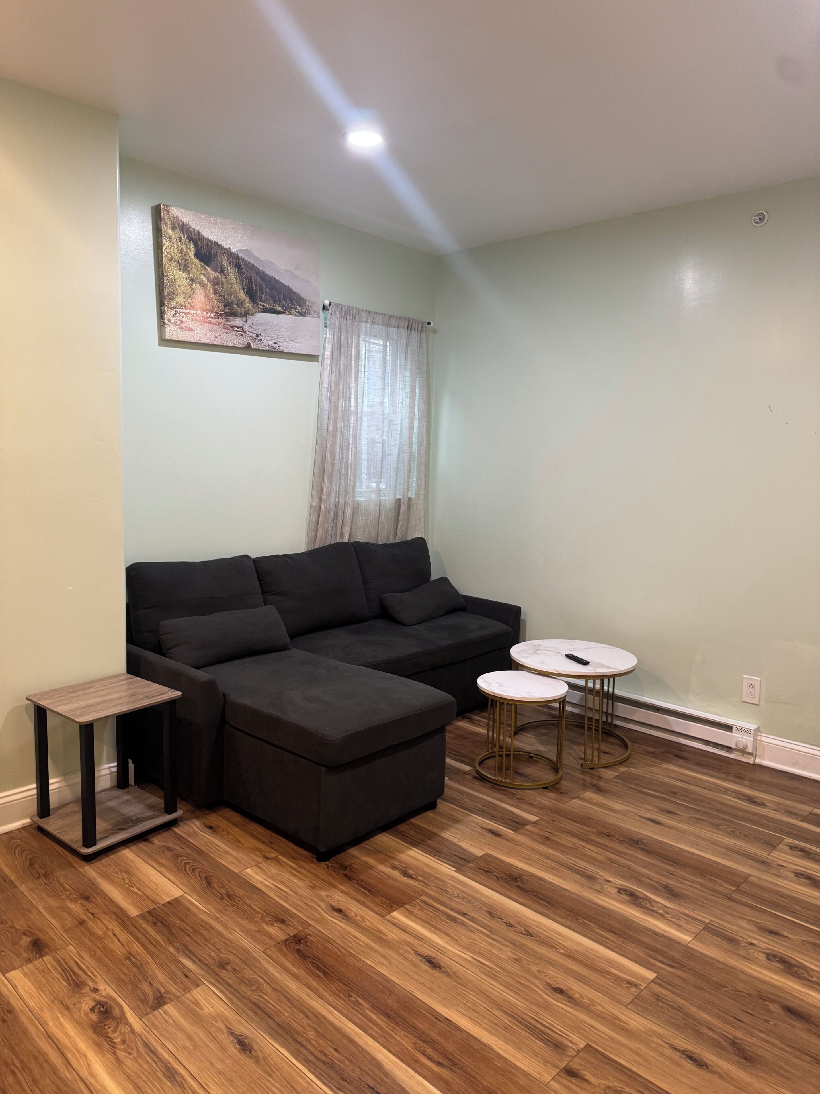 A living room with a sectional sofa, a small side table, a round coffee table, and a painting on the wall.