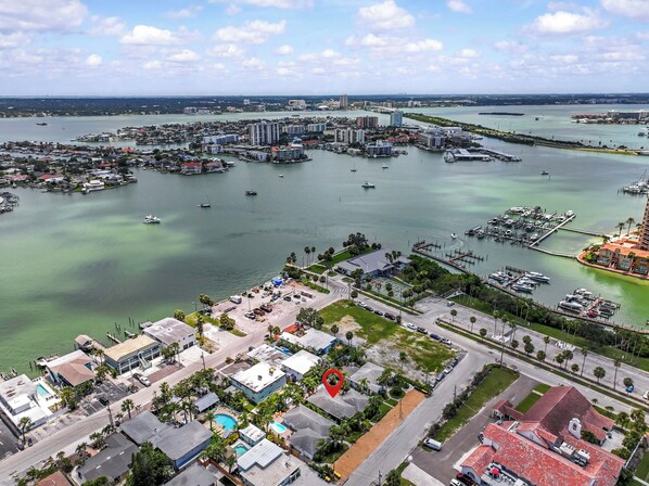 An aerial view of a coastal city with a marina, buildings, and a clear sky.