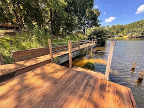 A wooden dock extending into a lake, surrounded by greenery and trees.