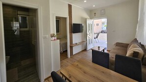 Un salon moderne avec une table à manger en bois, un canapé et un téléviseur fixé au mur.