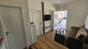 Un salon moderne avec une table à manger en bois, un canapé et un téléviseur fixé au mur.