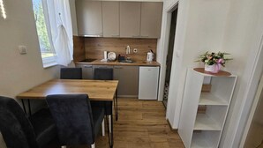 Une cuisine de taille réduite, avec une table et des chaises en bois, un petit réfrigérateur et un évier.
