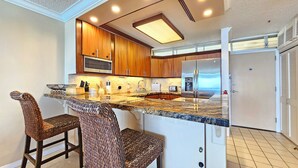 Una cocina con armarios de madera, un refrigerador de acero inoxidable y una encimera de granito.
