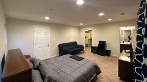 A bedroom with a bed, a dresser, a vanity, and a closet.