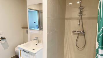 Et moderne badeværelse med bruser, vask og toilet.