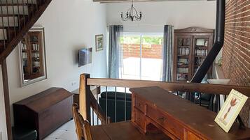 Amplia habitación con una mesa de comedor de madera, una escalera y vistas al exterior.