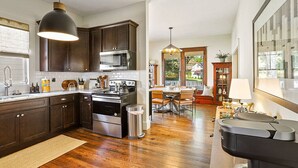 Una cocina moderna con gabinetes de madera oscura, electrodomésticos de acero inoxidable y una zona de comedor con una mesa redonda y sillas.