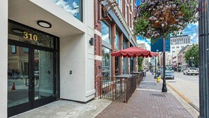 Un escaparate con puerta de cristal, el número '310' en la parte superior y mesas al aire libre con sombrillas rojas.
