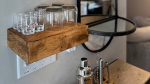 Een houten wijnrek met glazen en kleine potjes.