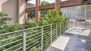 A pedestrian bridge with a metal railing, brick walls, and greenery.