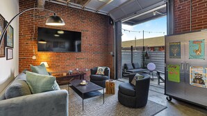 Un espace de détente moderne avec un mur en briques, un téléviseur à écran plat, des sièges confortables et une grande fenêtre.