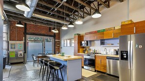 Une cuisine moderne dotée d’un îlot central, d’appareils électroménagers en acier inoxydable et d’un mur en briques.