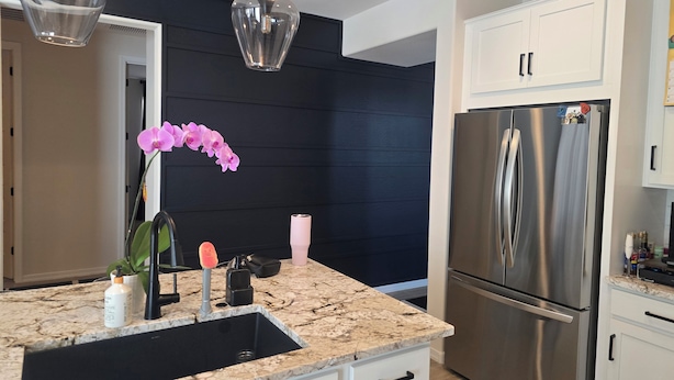 A modern kitchen with a black accent wall, stainless steel appliances, and a marble countertop. - Pleasant 3-bedroom house with AC in San Tan Valley (San Tan Valley)