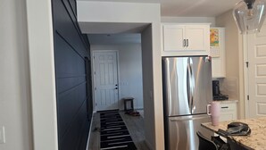 A modern kitchen with a stainless steel refrigerator, white cabinets, and a marble countertop. - Pleasant 3-bedroom house with AC in San Tan Valley (San Tan Valley)