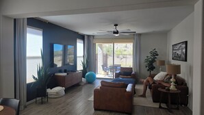 A spacious living room with a large window, a ceiling fan, and a view of the outdoors. - Pleasant 3-bedroom house with AC in San Tan Valley (San Tan Valley)